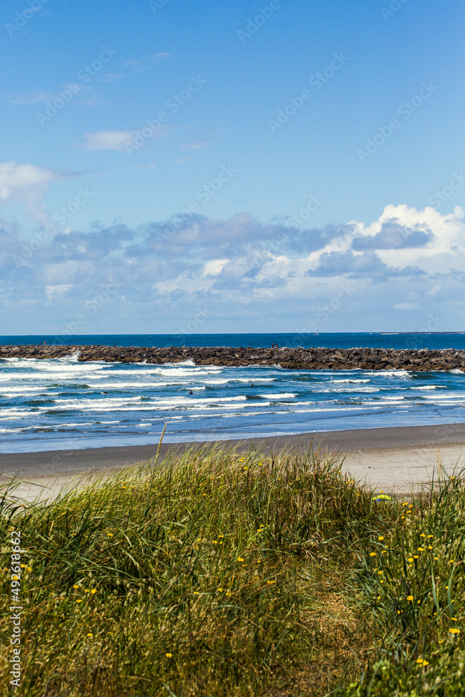 Empty beach with waves crashing and a seawall in distance