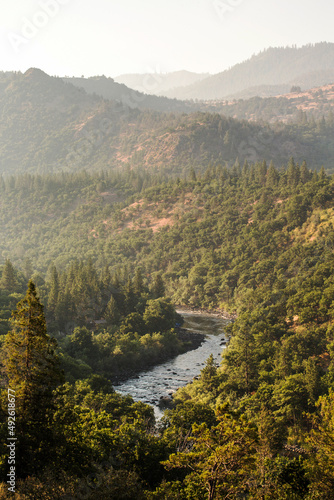 Фотография A river flows through forested hills at sunset