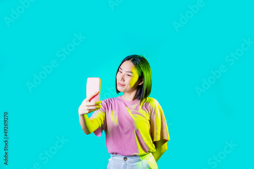 Young asiatic woman isolated using smartphone taking selfie videocalling