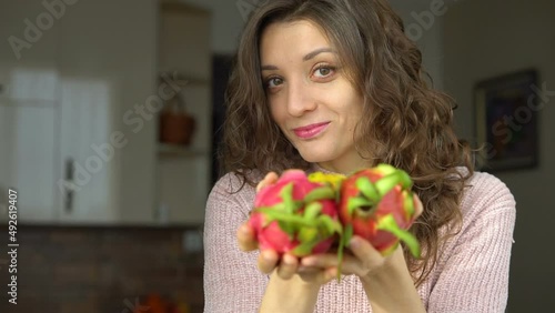Young girl is holding two fresh ripe organic dragon fruits or pitaya, pitahaya. Exotic fruits, healthy eating concept