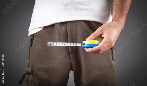 Man with a measuring tape measures his penis size.
