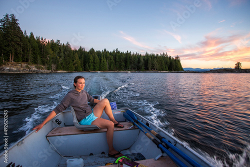 A young woman in steers a small boat at sunset