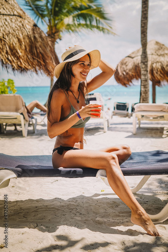 Woman posing in a bikini with a cocktail on a tropical beach photo