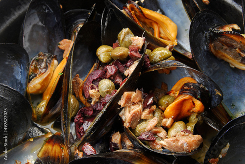 Mussels in a saucepan, delicious mussels with capers on white background, close up view