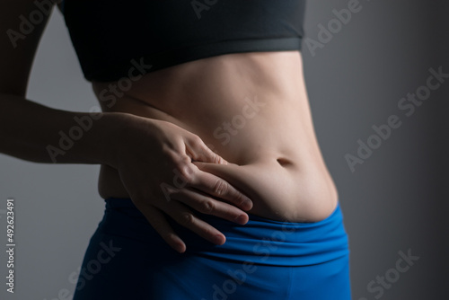 Woman holding and pushing the skin of the stomack cellulite.