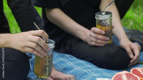 Men's hands hold a glass with a drink at a picnic in the park in summer. LGBT