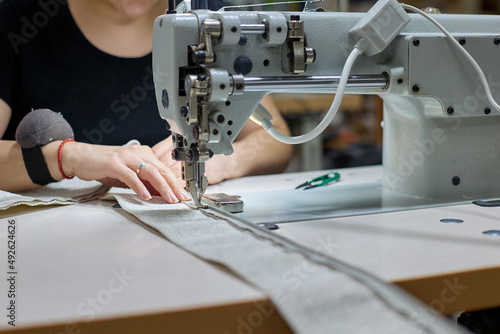 Obraz na plátne Seamstress is sewing beige fabric in a sewing workshop