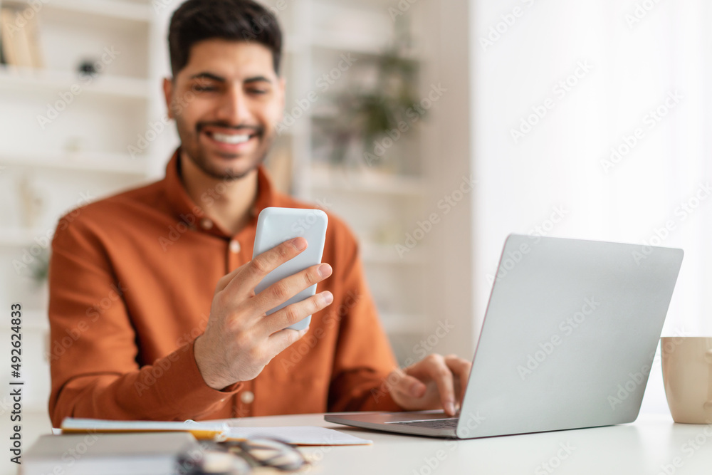 Portrait of smiling man using smartphone and pc at home Portrait of smiling man using smartphone and pc at home