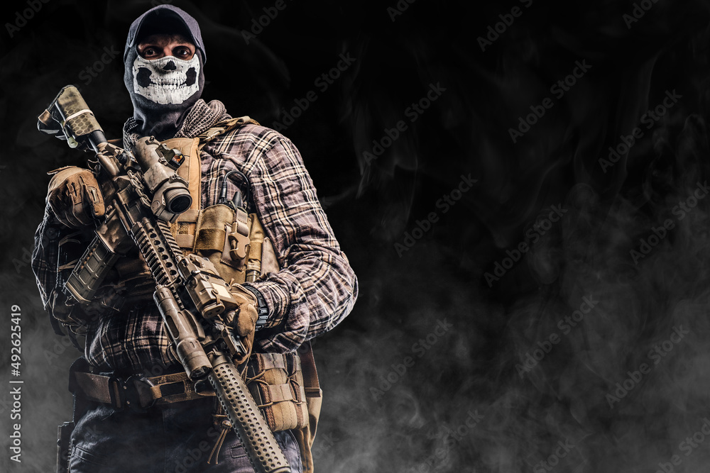 Combative soldier with mask holding rifle against black background