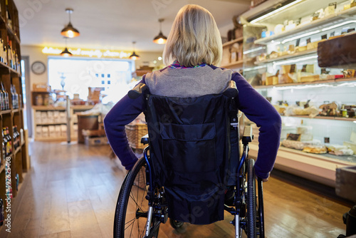 Rear View Of Woman In Wheelchair Shopping For Food In Delicatessen © Daisy Daisy