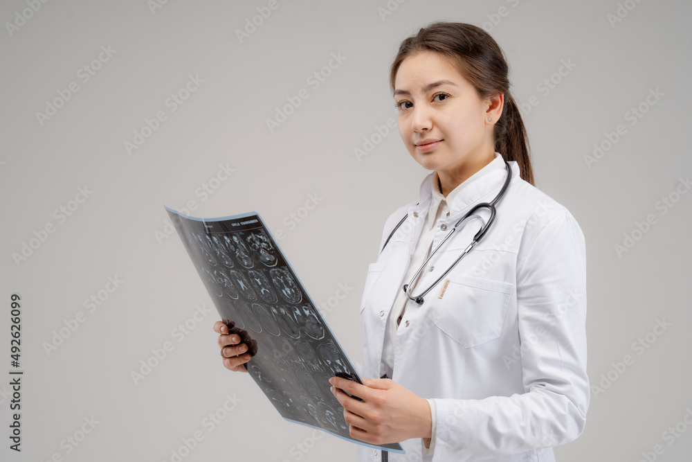 Female doctor with stethoscope looking at x-ray on the gray background Female doctor with stethoscope looking at x-ray on the gray background