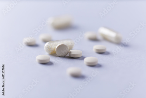 Vitamin C tablets and capsules on bright paper background. Close up. Copy space. 