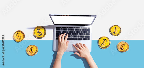 Foto Person using a laptop computer with coins - earn online - work from home themes