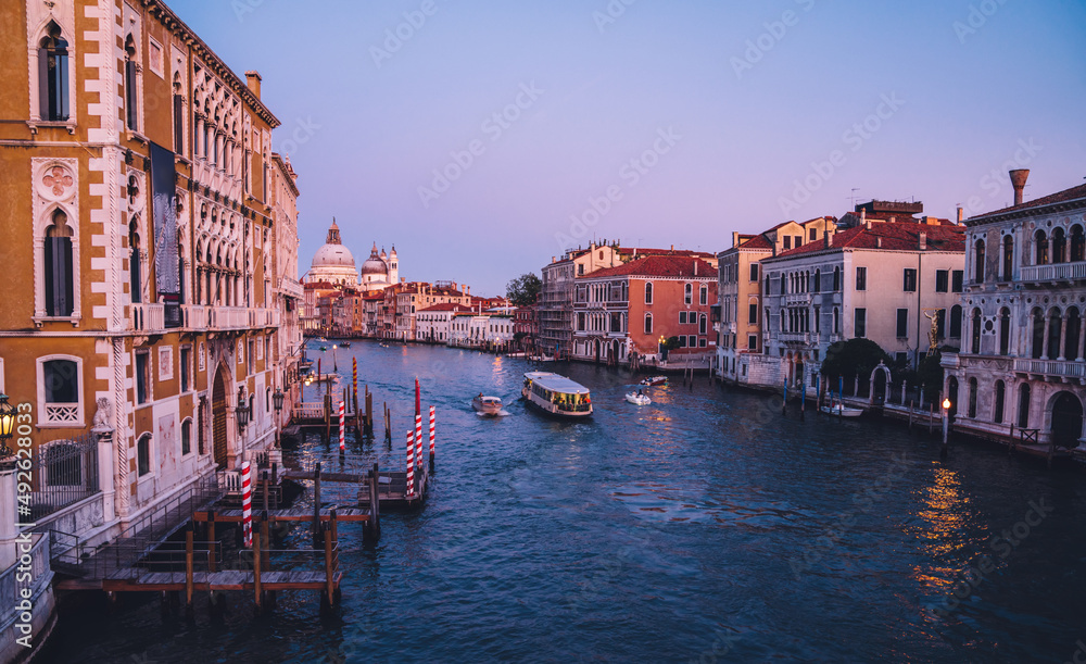 Motorboat taxi transport floating in Venecian gran Canal during evening time for romantic sightseeing excursion, scenery view on ancient architecture buildings and monument showplaces in Italy