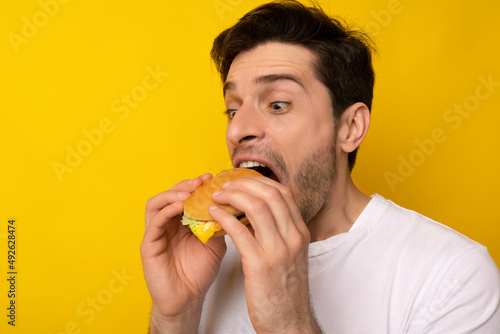 Funny Hungry Guy Holding Burger Biting Sandwich At Studio