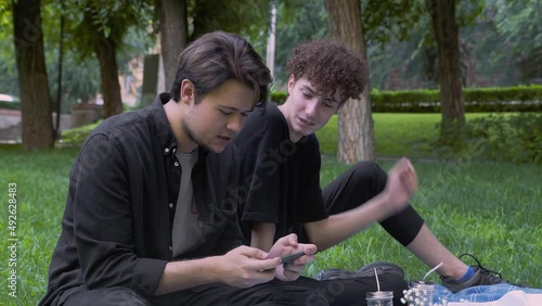The guy plays the game on the phone, and the second watches the process in nature in the summer. LGBT