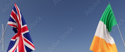 Flags of Great Britain and Ireland on flagpoles on sides. Flags on a blue background. Place for text. England, London. The United Kingdom. Dublin. Commonwealth. 3D illustration.