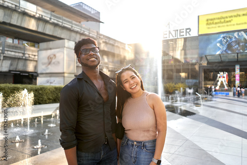 Portrait of two multiracial friends smiling and stanging on a mall photo