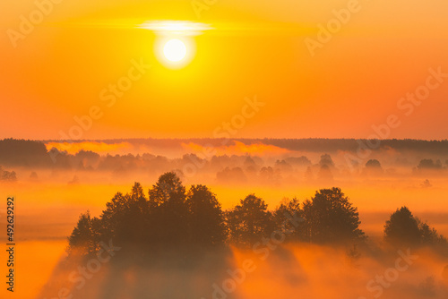 Amazing Sunrise Sunset Over Misty Landscape. Scenic View Of Foggy Morning Sky With Rising Sun Above Misty Forest And River. Early Summer Nature Of Eastern Europe.