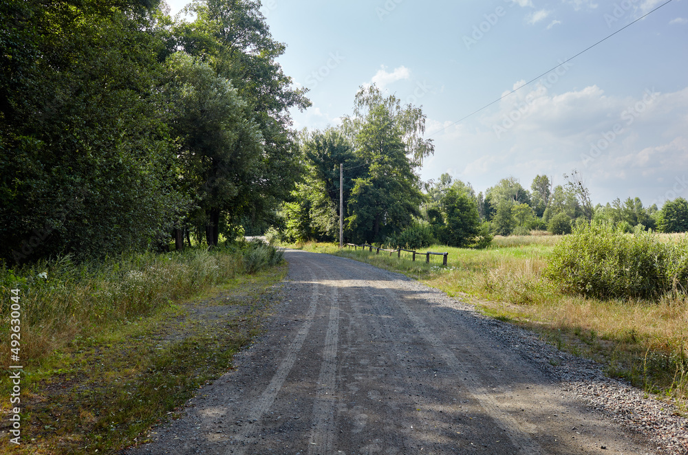 Fototapeta premium A gravel road at rural Europe. Suburban road path