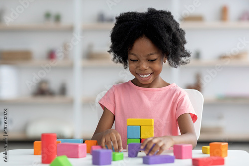 Smiling little african american girl playing with colorful wooden blocks