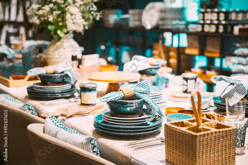 View of assortment of decor for interior shop in store of shopping center. Home accessories and household products for dining room in store of shopping centre. View of dinnerware, plate, bowl on table photo