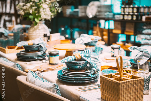 View of assortment of decor for interior shop in store of shopping center. Home accessories and household products for dining room in store of shopping centre. View of dinnerware, plate, bowl on table