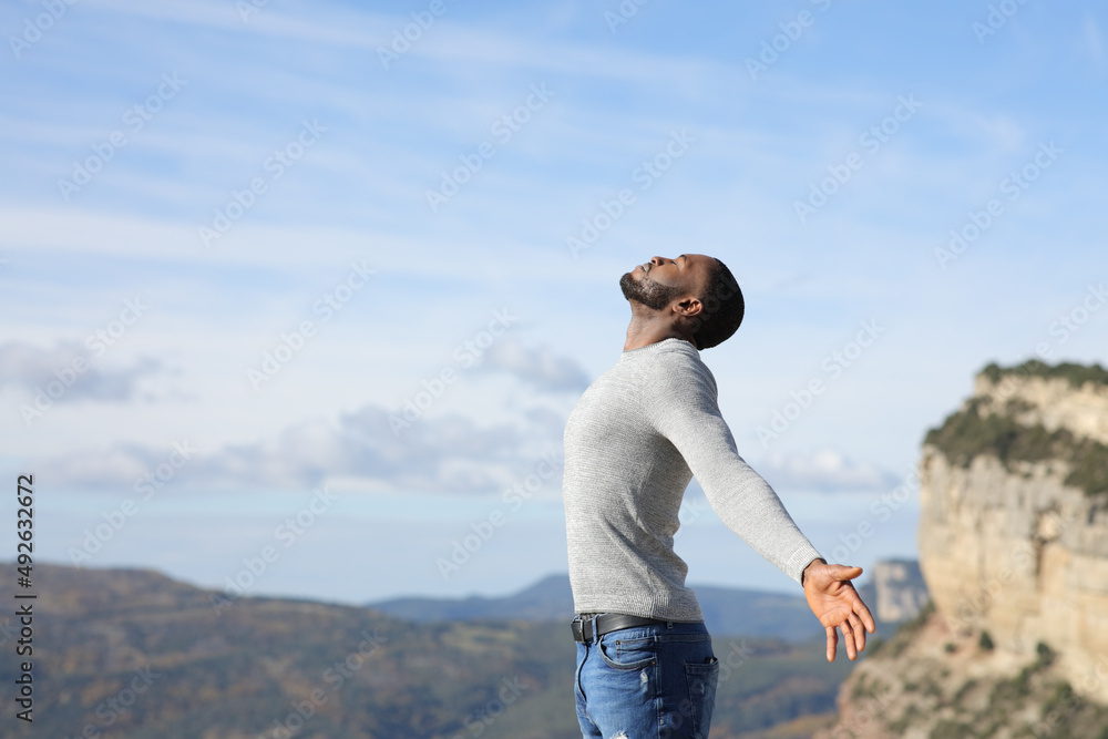 Man with black skin breaths fresh air in nature