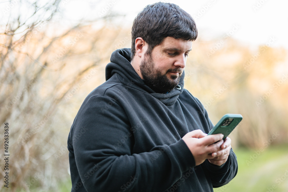 Obese man checks mobile phone Obese man checks mobile phone