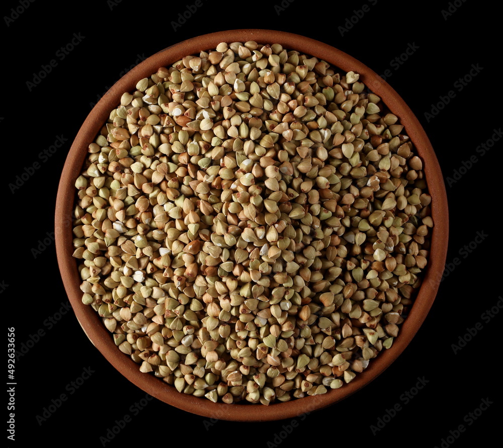 Buckwheat green seed pile in clay pot, bowl isolated on black, top Buckwheat green seed pile in clay pot, bowl isolated on black, top