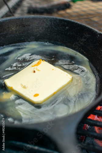 mantequilla derretida con romero en sarten de hierro sobre la parrilla.mantequilla derretida condimentada en el asador.
