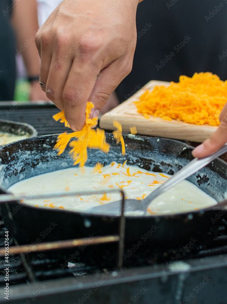 queso cheddar amarillo rallado y agregado en sarten para preparar salsa de queso  

queso cheddar 

queso 

cheddar 