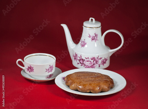 On the table on a red tablecloth a cup of tea and a delicious national gata