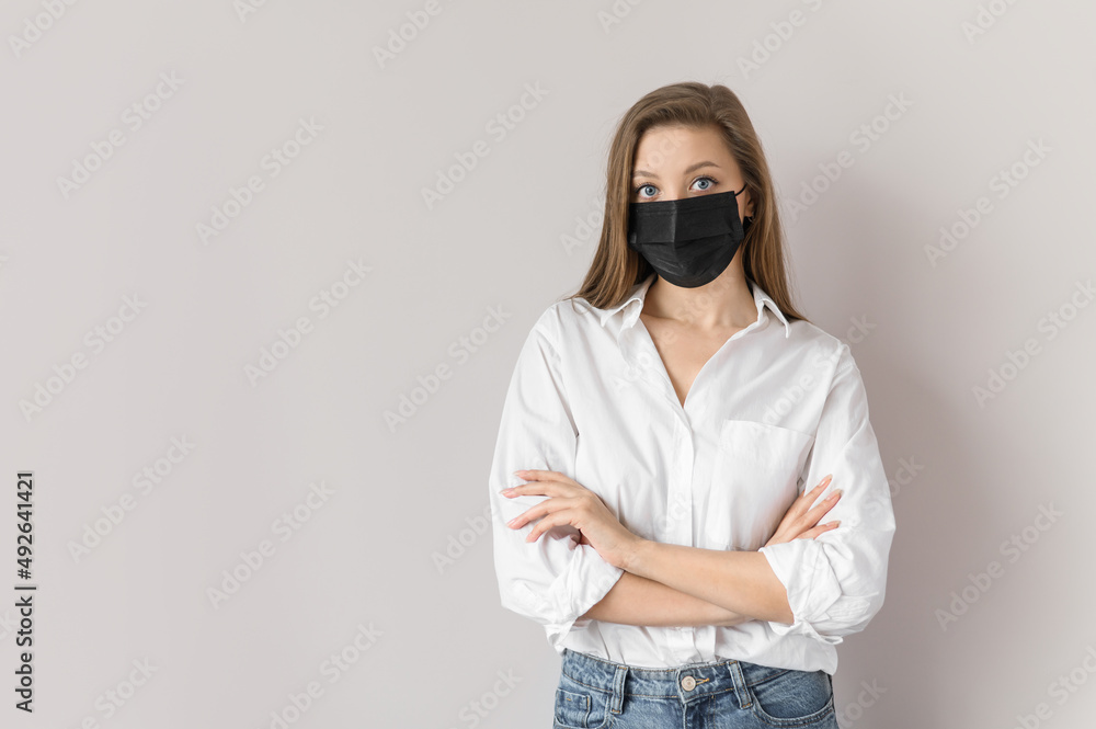 A young girl in a black mask on a light background. Preventing the virus into a pandemic.Isolated close up portrait. A young girl in a black mask on a light background. Preventing the virus into a pandemic.Isolated close up portrait.