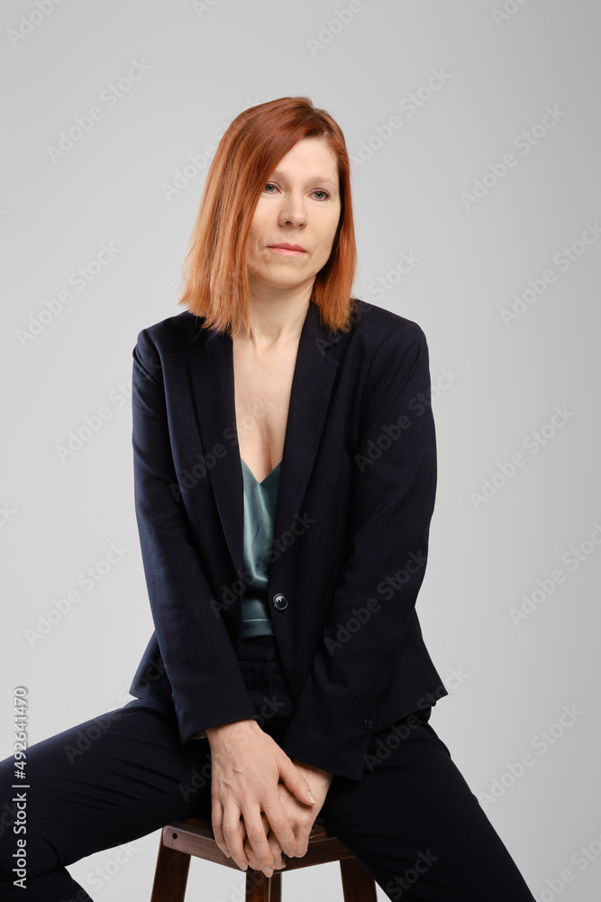 Stylish middle aged woman in pantsuit sitting in studio Stylish middle aged woman in pantsuit sitting in studio