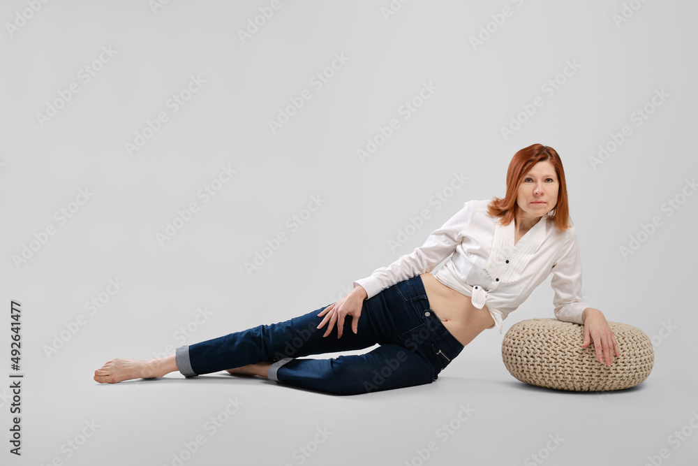 Barefoot middle age woman leaning on padded stool