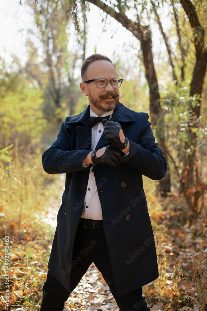 A stylishly dressed man with glasses, a beautiful autumn forest and a river. Elderly Brit. A stylishly dressed man with glasses, a beautiful autumn forest and a river. Elderly Brit.