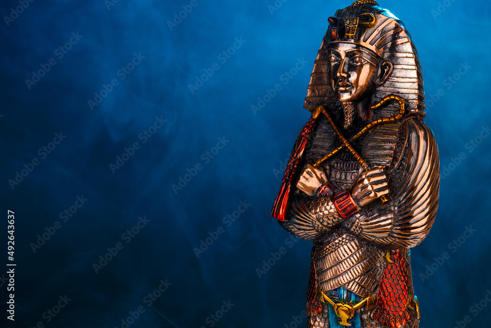 golden Egyptian pharaoh figurine in blue smoke on a black background. Stock  Photo | Adobe Stock