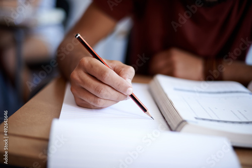 Developing good study habits. Closeup shot of a young student writing on a note pad. photo