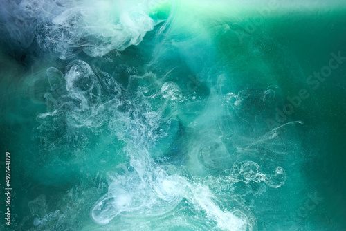 Green smoke on white ink background, colorful fog, abstract swirling emerald ocean sea, acrylic paint pigment underwater photo