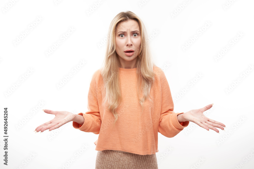 Shocked blond girl looks surprised spreads her arms on white studio background with copy space Shocked blond girl looks surprised spreads her arms on white studio background with copy space