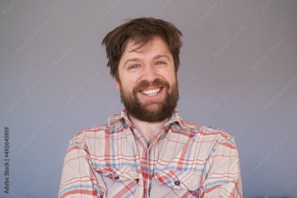 Fototapeta premium Happy young bearded guy looking at camera, brightfully smiling with teeth