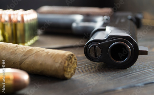 Legendary U.S. Army handgun Colt 1911A1 with .45 bullets and a cigar on wooden background, gangster mafia and war concept