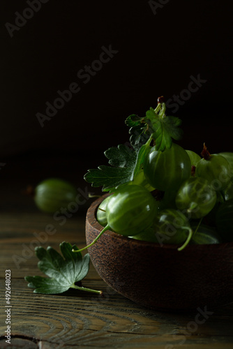 juicy gooseberry berries in a wooden cup on a dark background. High quality photo