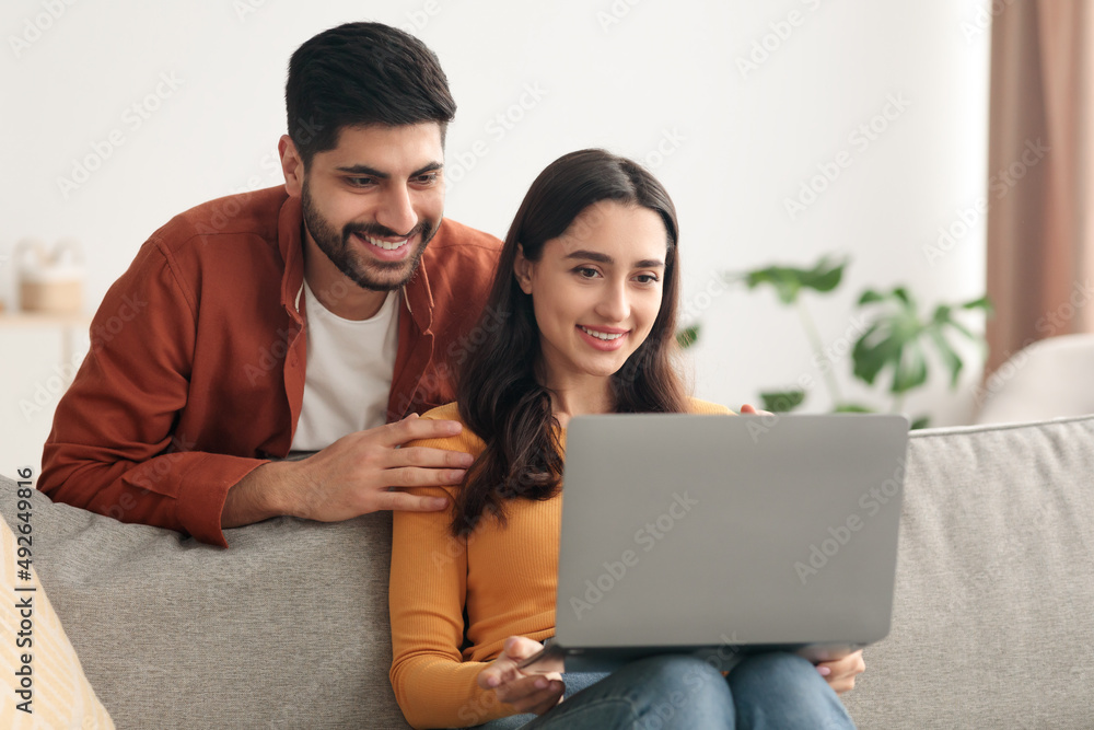 Middle Eastern Spouses Using Laptop Watching Movie Sitting At Home Middle Eastern Spouses Using Laptop Watching Movie Sitting At Home