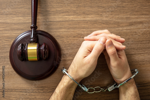 Handcuffed Convict. Court sentence Prison. Handcuff locked and judge gavel on table, top view.. photo