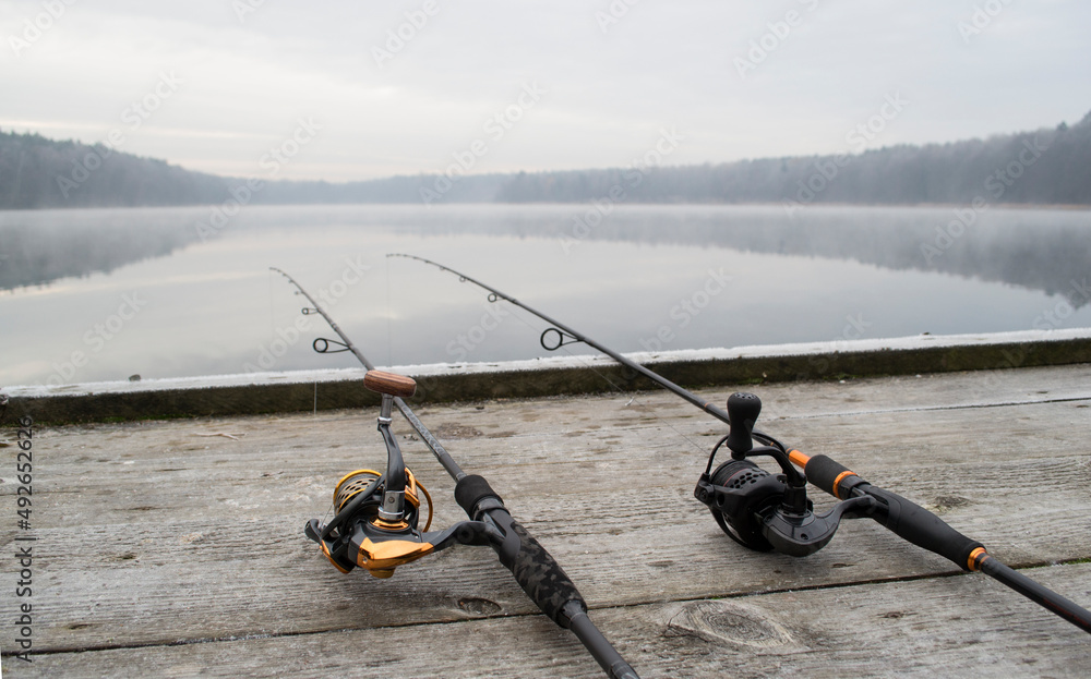 Fishing rod, spinning reel on the wooden background pier river