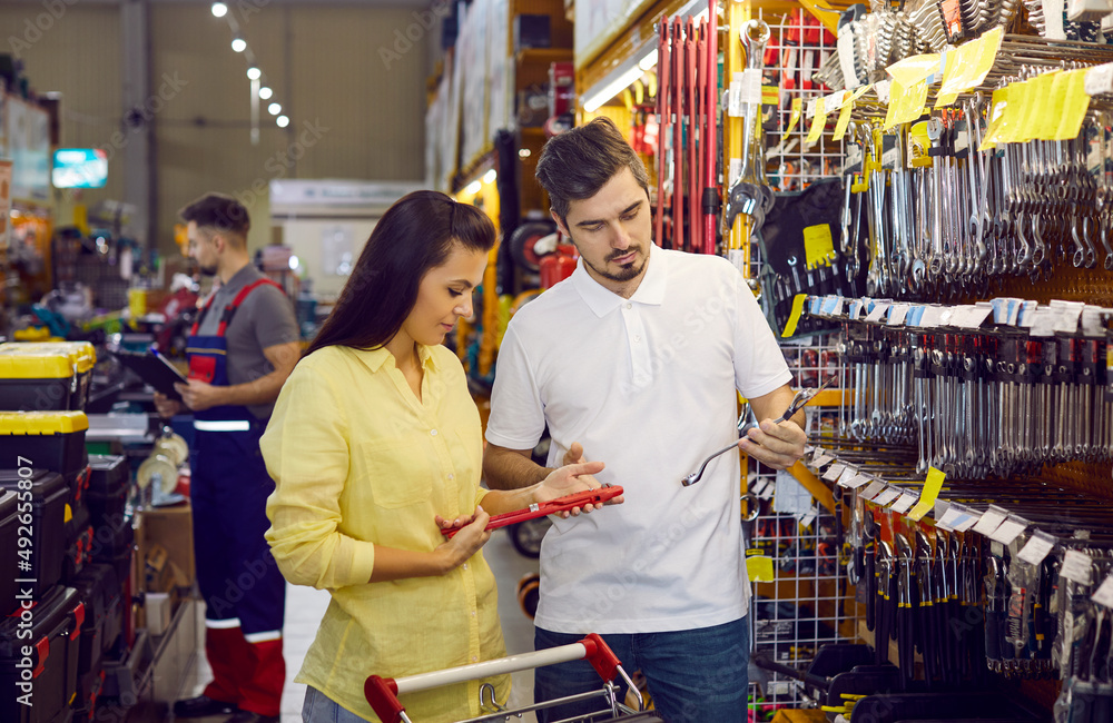 Customers shopping at a DIY store. Young married couple shopping for tools at a modern hardware store. Husband and wife together buying stuff for renovating the house and doing different home repairs