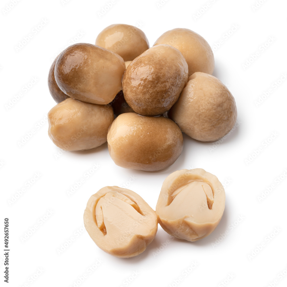 Heap of whole and halved straw mushrooms close up isolated on white background