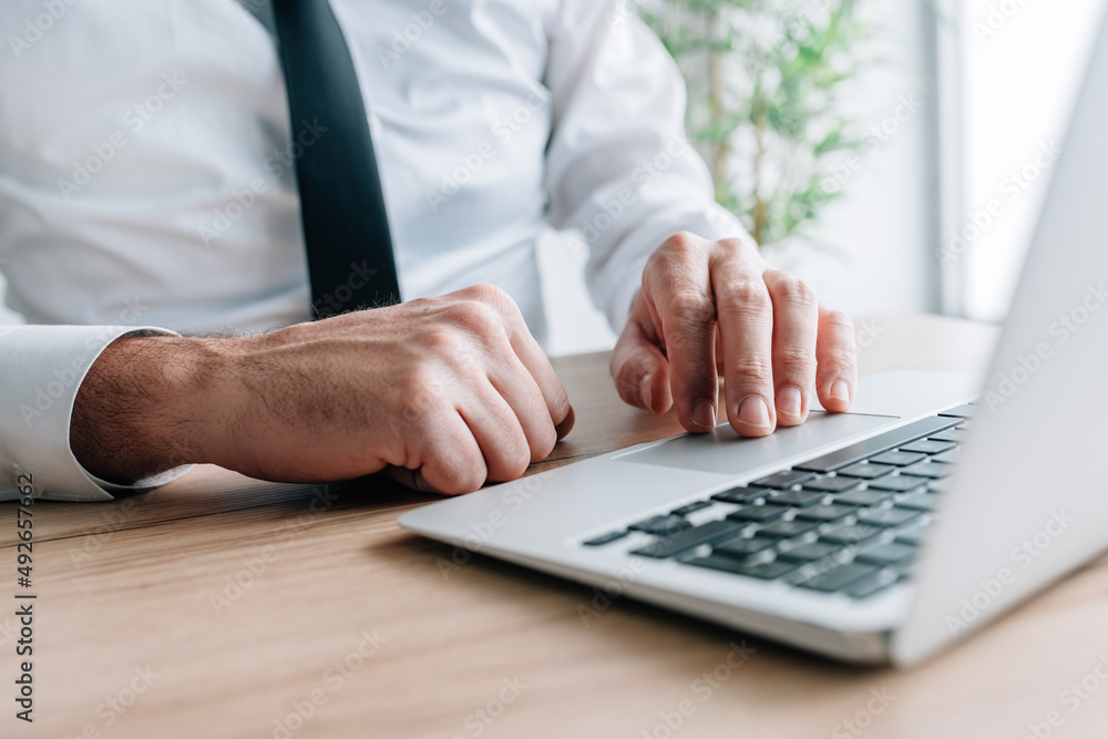 Businessman using laptop computer at office desk, hand on a trackpad or touchpad Businessman using laptop computer at office desk, hand on a trackpad or touchpad